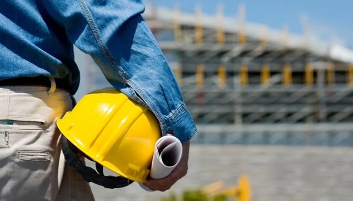 Muratore che tiene il suo casco da lavoro in mano